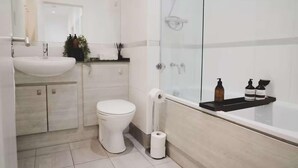 Un baño moderno con lavamanos, inodoro y cabina de ducha de vidrio.