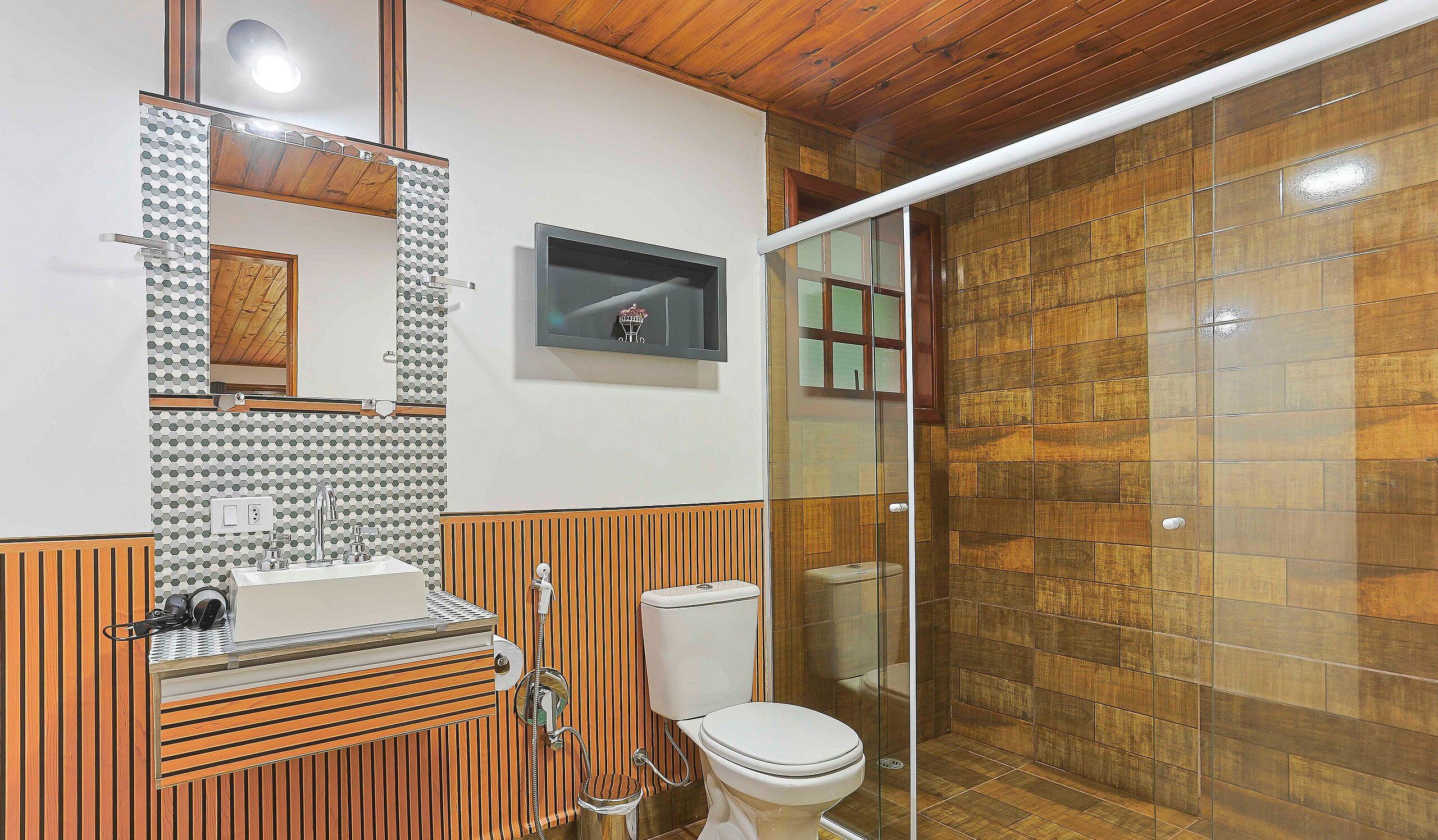 Baño con tocador de madera, inodoro y cabina de ducha.