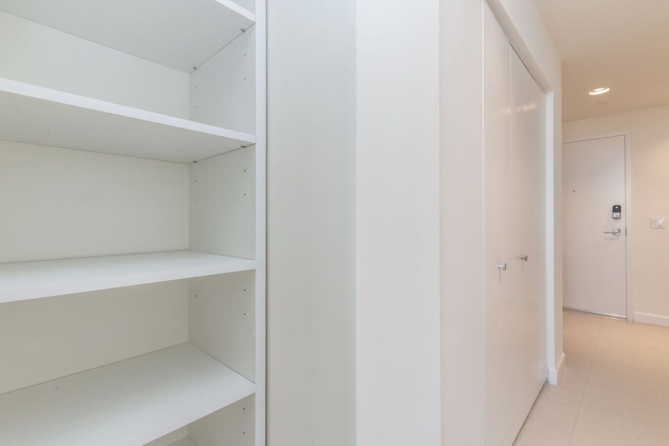 A hallway with white walls and a door at the end.