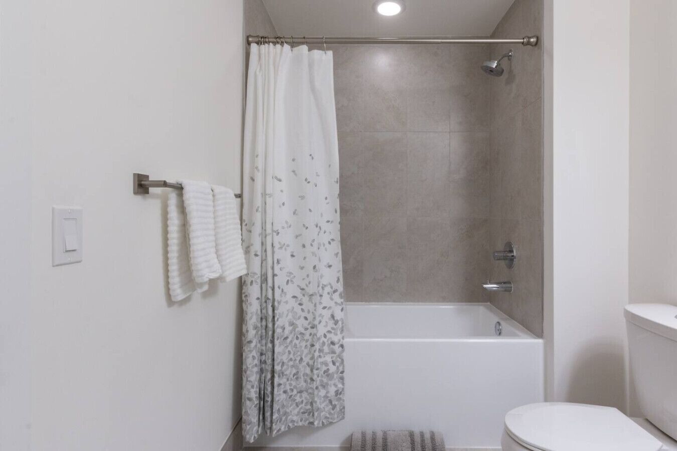 A modern bathroom with a shower, bathtub, and toilet.