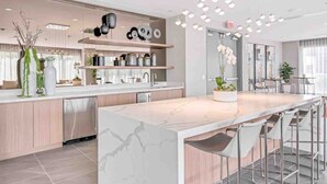 A modern kitchen with a marble island, stainless steel appliances, and pendant lighting.