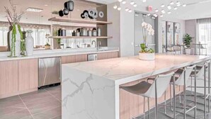 Une cuisine moderne dotée d’un îlot en marbre, d’appareils électroménagers en acier inoxydable et d’un coin bar avec des tabourets.