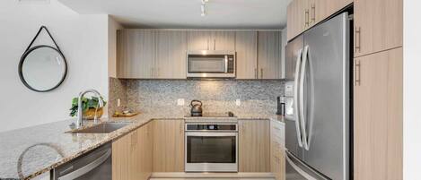 A modern kitchen with wooden cabinets, stainless steel appliances, and a granite countertop.