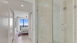 Une chambre d’hôtel moderne dotée d’une douche en verre, d’un lit avec vue et d’un balcon.
