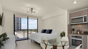A modern bedroom with a balcony, a dining area with a glass table, and a kitchen with a microwave and oven.