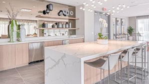 A modern kitchen with a marble island, stainless steel appliances, and a bar area with stools.
