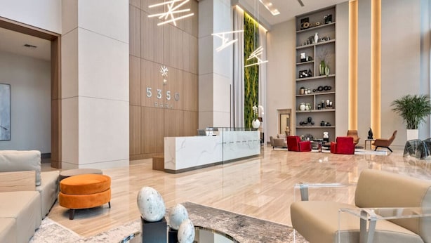 A modern lobby with a reception desk, seating area, and a large wall with a vertical garden.