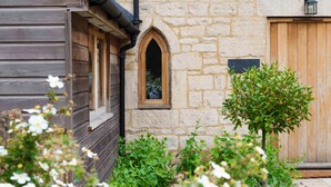 A stone building with a wooden door and a window with an arch. - Lemon Tree Cottage - Luxury Cottages (Painswick)