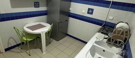 A compact kitchen with a refrigerator, a sink, and a small dining area with a table and chairs.