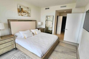 Une chambre d’hôtel moderne avec un grand lit, des tables de chevet, un miroir et une armoire.