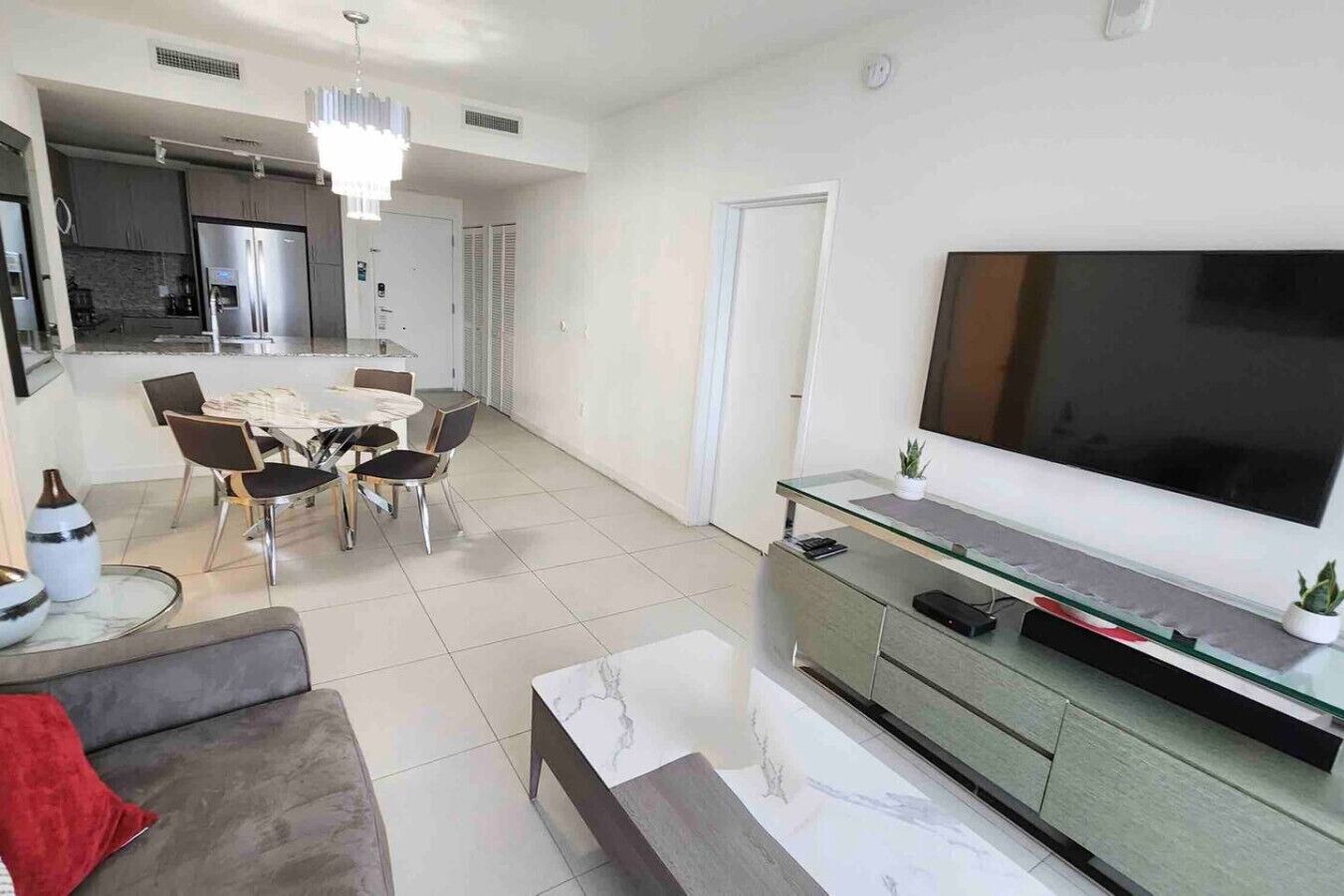 Una sala de estar moderna con un sofá, una mesa de centro, un televisor y un comedor con sillas y una mesa.