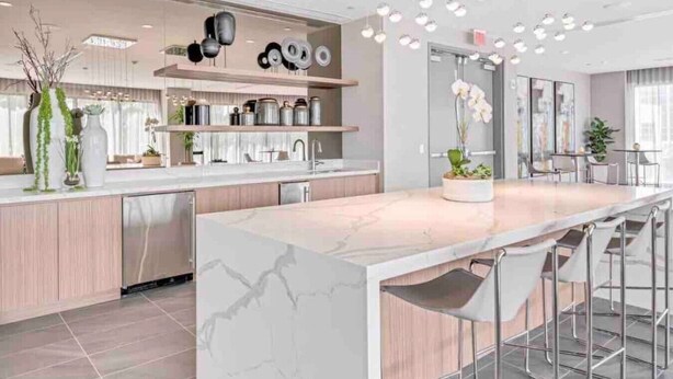 Une cuisine moderne dotée d’un îlot en marbre, d’appareils électroménagers en acier inoxydable et d’un coin bar avec des tabourets.