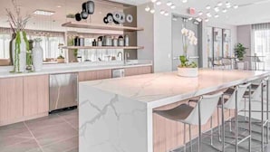 A modern kitchen with a marble island, stainless steel appliances, and a bar area with stools.