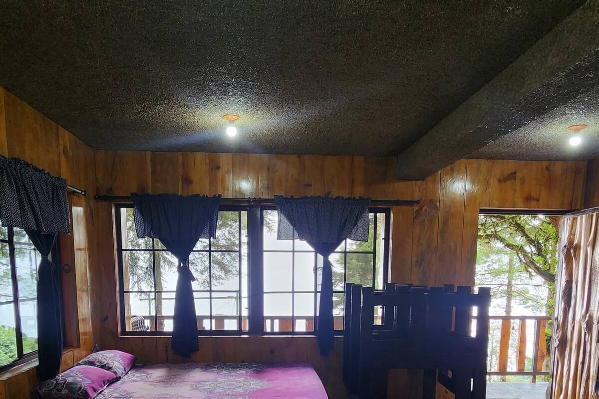 A room with a bed, a chair, and a view of the outdoors.