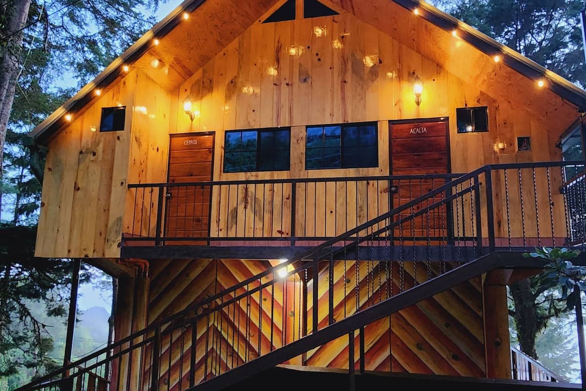 A wooden cabin with a balcony, a staircase, and a small deck area.
