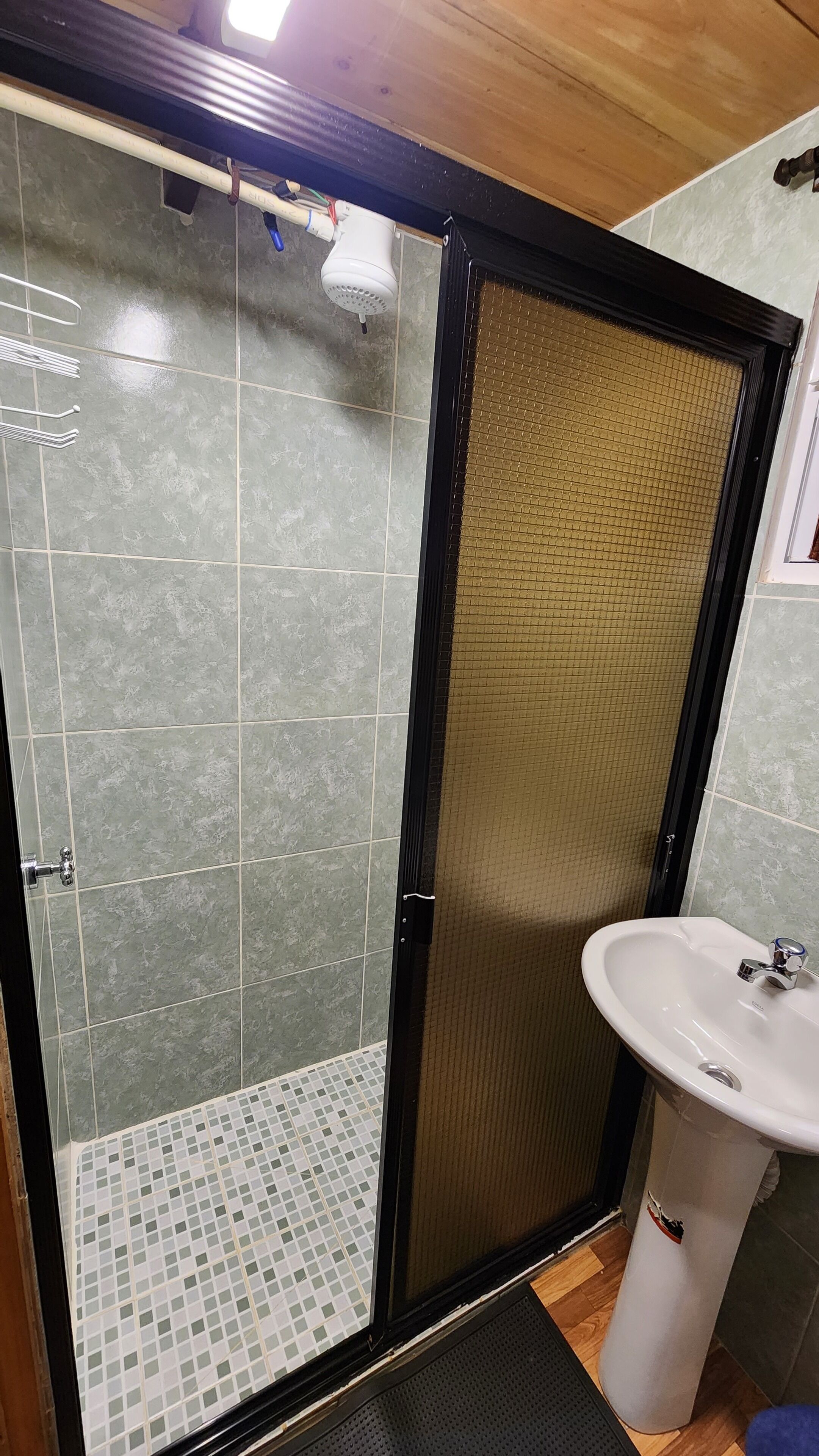Une salle de bain avec un espace douche, un lavabo et un revêtement de sol carrelé.