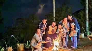 A group of people gathered around a campfire in a wooded area at night.