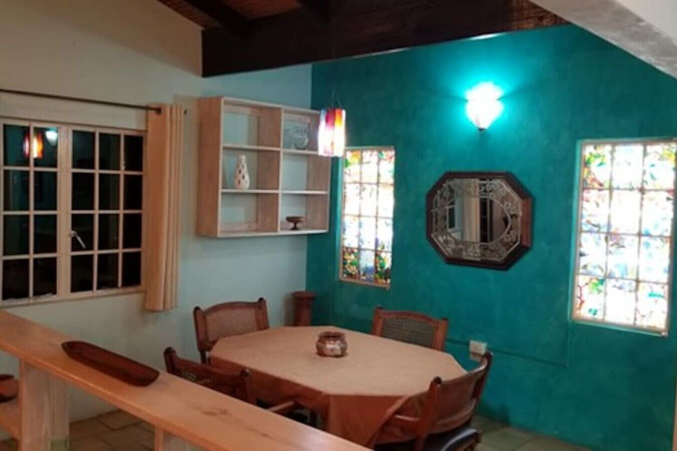 A dining area with a wooden table and chairs, a cabinet with glass doors, and a wall-mounted mirror.