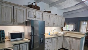 Une cuisine équipée d’un réfrigérateur, d’un four à micro-ondes, d’une cuisinière et de placards.