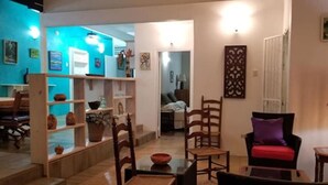 Un salon avec un coin repas, une cuisine à l’arrière-plan et un escalier menant à l’étage supérieur.
