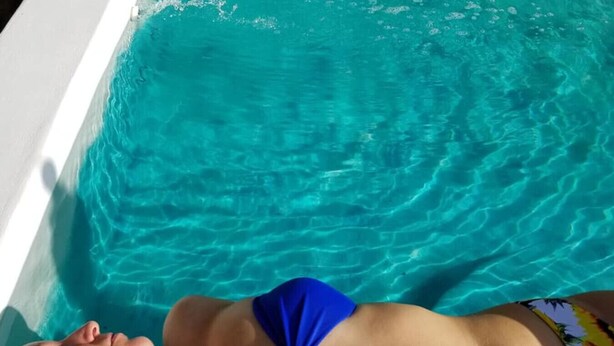 Una persona recostada en una piscina con agua cristalina.