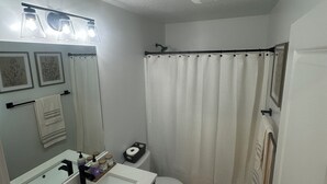 Une salle de bain avec un lavabo blanc, un miroir et un rideau de douche.