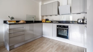A modern kitchen with white cabinets, a black countertop, and a built-in oven.