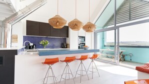A modern kitchen with a blue backsplash, stainless steel appliances, and a large window overlooking a scenic view.