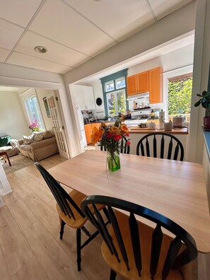 Una cocina moderna con armarios de madera, una mesa de comedor con sillas y un florero sobre la mesa.
