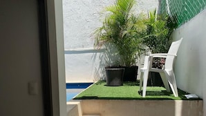 Ein kleiner Außenbereich mit einem weißen Plastikstuhl, einem Blumentopf und einer Betontreppe, die zu einem Pool führt.