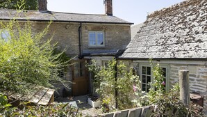 A stone house with a small garden, a wooden fence, and a window with shutters. - The Rabbit Hole | Cotswold Holiday Let | 1 Bed & Sleeps 2 (Langford, Lechlade)