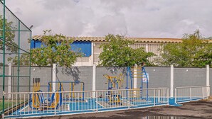 A playground with exercise equipment, a blue and white pool, and a fenced area.