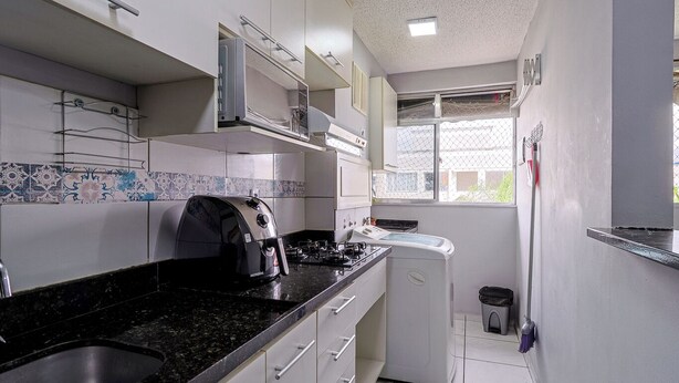 A compact kitchen with a gas stove, a coffee maker, and a washing machine.