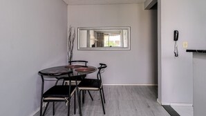 A compact dining area with a round table and four chairs, a mirror on the wall, and a telephone on the right.