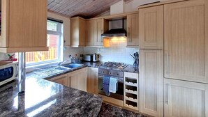 Eine Küche mit Holzausstattung, einem Gasherd, einer Spüle und einem Fenster.