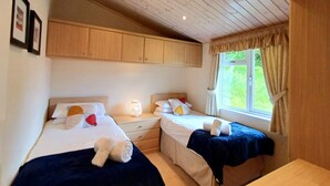 Ein Schlafzimmer mit zwei Betten, Holzboden und einem Fenster mit Vorhängen.