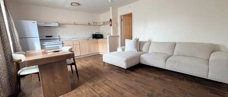 Un salon moderne avec une table à manger en bois, un canapé et un coin cuisine à l’arrière-plan.
