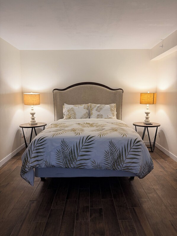 A bedroom with a bed, two bedside tables, and a headboard.