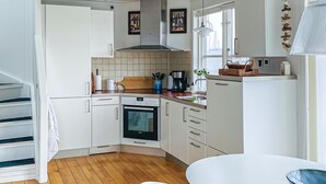 Ett modernt kök med vita skåp, en inbyggd ugn och en matplats med ett vitt bord och stolar.