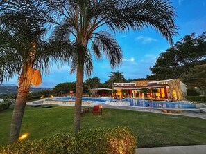 A resort with a pool area, palm trees, and a building with a stone facade.