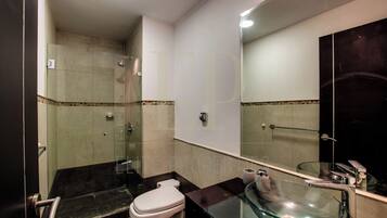 A modern bathroom with a glass sink, a toilet, and a shower area.