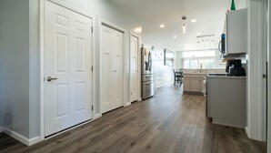 A modern kitchen with white cabinetry, a built-in oven, and a dining area with a table and chairs.