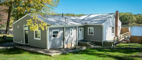 A small, single-story cabin with a front porch, a chimney, and a deck.