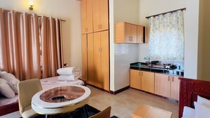 Een compacte hotelkamer met een eethoek, een kitchenette en een zithoek.