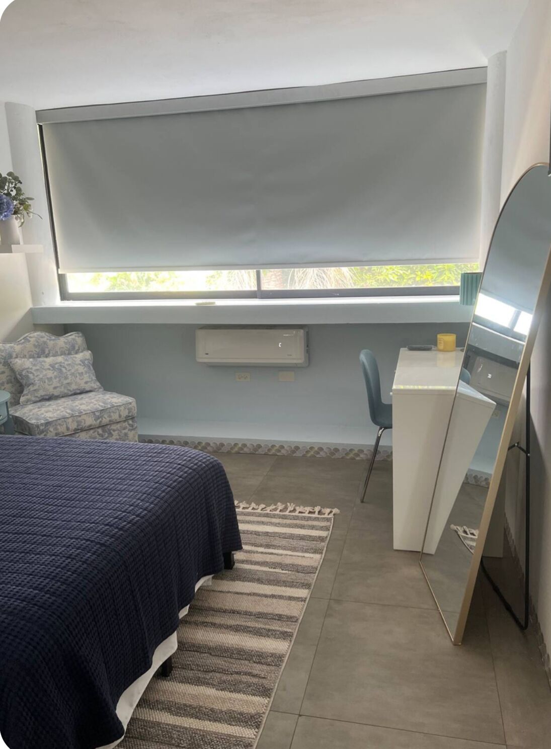 Une chambre à coucher avec un lit, un bureau, une chaise, une fenêtre et un miroir.