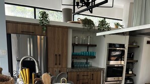Uma cozinha moderna com eletrodomésticos de aço inoxidável, bancada de granito e diversos utensílios.