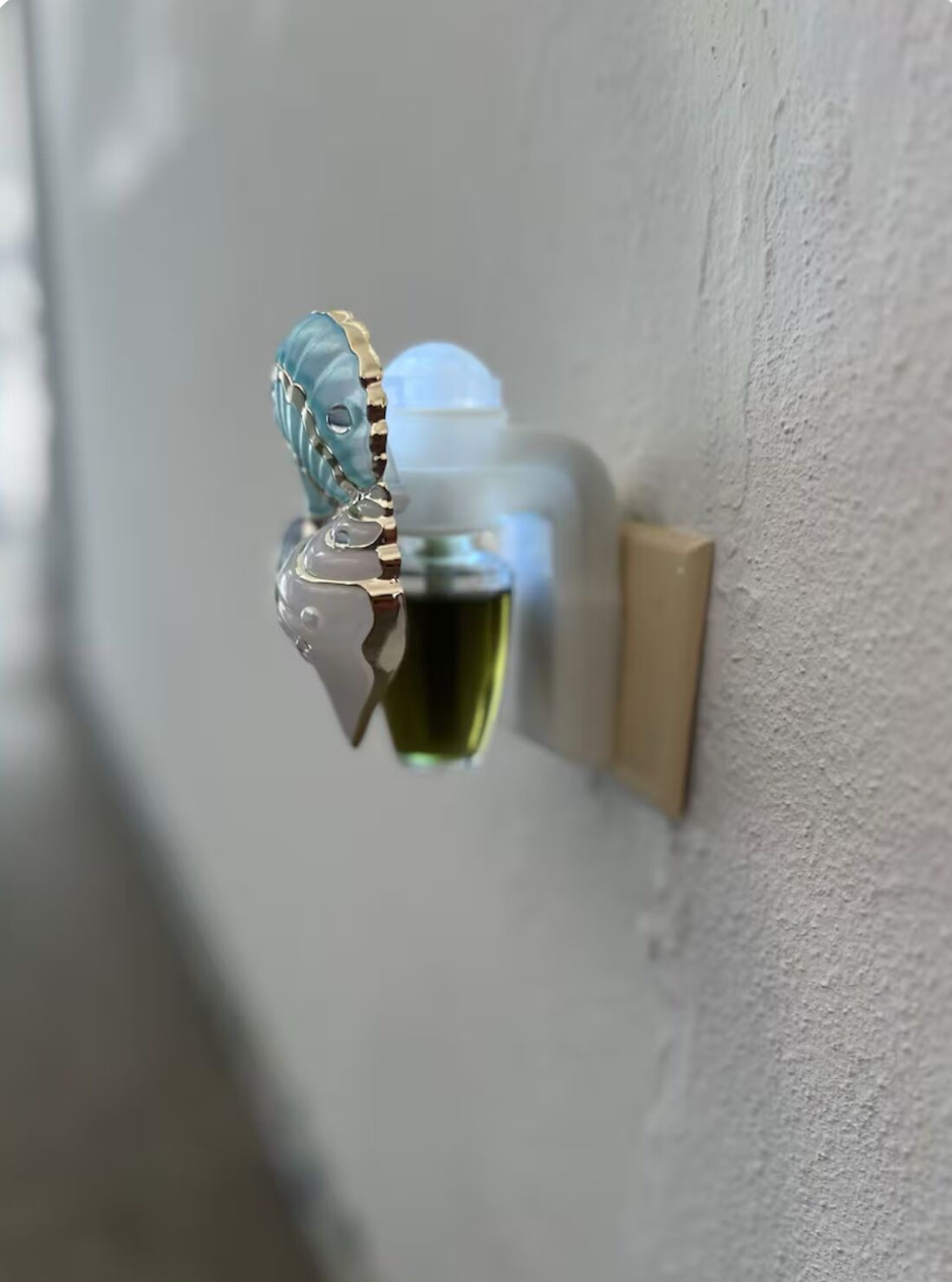 Een deurklink met een blauw en goud ontwerp, een lichtschakelaar en een wandlamp.