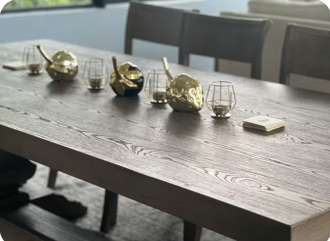 Une table en bois sur laquelle se trouvent plusieurs objets en verre et un objet de couleur dorée.
