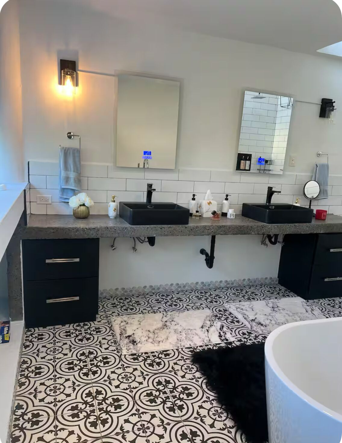 Une salle de bain avec deux lavabos, un grand miroir et un carrelage décoratif.