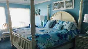A bedroom with a four-poster bed, a wooden chair, a nightstand, and a dresser.
